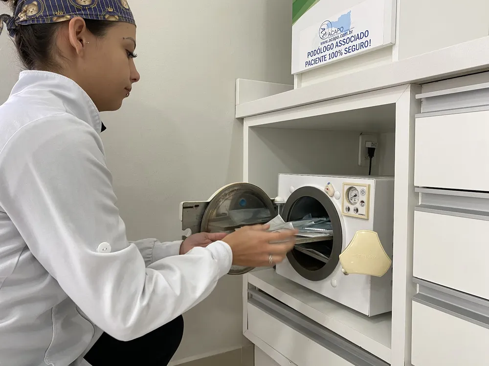 Sarah Bach Damasio colocando instrumentos embalados na autoclave do consultório